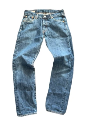 Levi's blå raka jeans - Klassiska blå jeans från Levi's med rak passform. Jeansen har en ljus tvätt och synliga sömmar i kontrastfärg. Tillverkade i slitstark denim med knappgylf och läderpatch bak i midjan. W 30 L 32