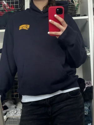 Mörkblå Billionaire Boys Club hoodie - Säljer en mörkblå hoodie från Billionaire Boys Club med gul logga på bröstet. Hoodien har en klassisk huva och stor magficka framtill. Perfekt för dig som gillar streetwear och vill ha en skön och stilren look. Materialet känns mjukt och bekvämt. Öppen för förhandling vid snabb affär!