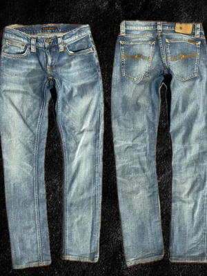 Blåa faded jeans från Nudie  - W26,L32Säljer ett par klassiska blå jeans från Nudie Jeans med raka ben och snygga slitningar. Jeansen har fem fickor, orange sömmar och Nudie-logga på bakfickan. Tillverkade i slitstark denim som ger en avslappnad och cool look.