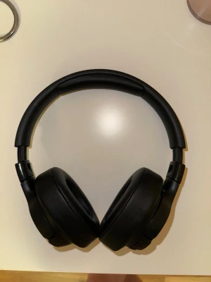 Svarta over-ear hörlurar från JBL - Säljer ett par snygga svarta over-ear hörlurar från JBL. De har en stilren design med vadderad bygel och mjuka öronkuddar i konstläder för extra komfort. Laddsladd ingår