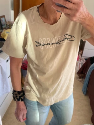 Beige t-shirt från Jack & Jones - Snygg beige t-shirt från Jack & Jones med trycket 'DENIM Originals' i vitt och svart på bröstet. Klassisk rund halsringning och korta ärmar. Tillverkad i mjuk bomull som känns skön mot huden. Perfekt för en avslappnad och stilren look.