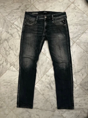 Gråa slim fit jeans replay - Snygga gråa slim fit jeans från replay med slitna detaljer och klassisk femficksdesign. Jeansen har en lätt tvättad look och raka ben. Perfekta för en avslappnad och trendig stil. Storlek L30 W32