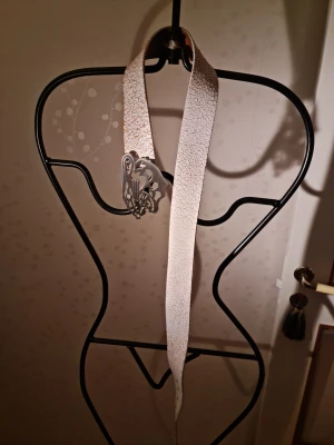 Vitt skärp från Tiger of Sweden - Snyggt vitt skärp från Tiger of Sweden med sprucken effekt på ytan och ett coolt silverfärgat spänne. Skärpet är gjort i skinn och har en unik design som sticker ut. Perfekt accessoar för att lyfta din outfit.