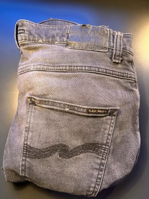 Grå jeans från Nudie Jeans - Liten igensytt hål i skrevet som Nudie själva lagade. Passar perfekt på 1.80 kille