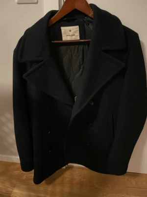 Peacoat Jack & Jones - Stilren skepparkavaj från Jack & Jones med bred krage och dubbelknäppning. Kavajen har quiltat innerfoder och klassisk rak passform. Perfekt för dig som vill ha en tidlös och snygg jacka till höst, vår, eller vinter.