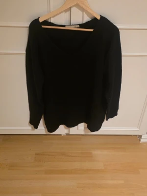 Svart stickad tröja med v-ringning - En enkel och stilren svart stickad tröja med djup v-ringning och långa ärmar. Oversize 