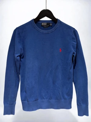Blå Polo Ralph Lauren - tröja  - Blå Polo Ralph Lauren-tröja med rund hals. Röd logga på bröstet, ribbade muddar. Tröjan är i mycket bra skick, inga defekter!                                      Storlek: S