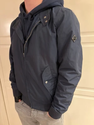  vindjacka från J.Lindeberg - Snygg marinblå vindjacka från J.Lindeberg med dragkedja framtill, två fickor med tryckknappar och ribbade muddar. Jackan är i perfekt skick samt ligger ute för ett bra pris, kom dm vid frågor✅