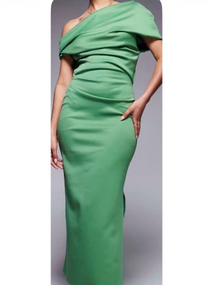 Grön långklänning asos design - Säljer en stilren grön långklänning med enkel design. Klänningen är sydd i ett mjukt polyestertyg som faller snyggt längs kroppen. Perfekt för dig som gillar minimalistisk stil och vill ha en klänning med clean look.