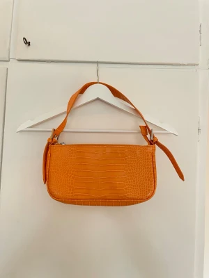Orange liten handväska  - Liten orange handväska med dragkedja upptill från Gina Tricot. Perfekt väska för att liva upp din outfit inför festival, fest eller semester! 