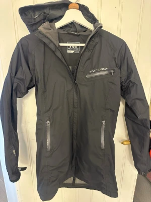 Svart regnjacka från Helly Hansen - Regn/vindjacka, saknar karborreband på vänsterarmen.