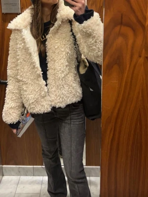 Krämvit teddyjacka  - Säljer en fluffig och trendig krämvit teddyjacka med stor krage och knappar. Perfekt för att hålla sig varm och snygg under kyliga dagar.
