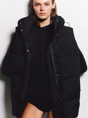 ZARA SVART VADDERAD VÄST - Säljer en svart, oversized dunväst med huva och dragkedja samt tryckknappar framtill. Västen har en quiltad design och är perfekt för lager-på-lager-stil. Passar dig som gillar streetwear och vill ha en cool look.