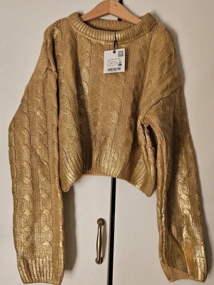 Guldig kabelstickad tröja - Snygg guldig stickad tröja med kabelmönster. Aldrig använd, ny med prislapp. Från Zara