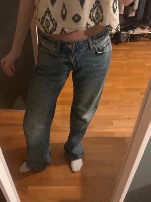 Blå baggy jeans med låg midja - Säljer ett par blå baggy jeans med låg midja och raka ben. Jeansen har klassisk femficksdesign och är gjorda i denim. Perfekta för en avslappnad och trendig look.