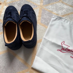 Mörkblå Louboutin skor - Säljer ett par mörkblå Christian Louboutin-sneakers i storlek 43. Skorna är i mycket gott skick, använda endast ett fåtal gånger. Påse medföljer. Perfekt för sommaren!☀️⛱️Pris: 1599kr.