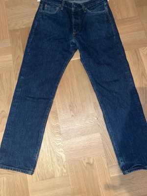 Dry/raw denim - Säljer ett par klassiska mörkblå jeans med rak passform och fem fickor. Jeansen har hög midja och är tillverkade i kraftig denim. Perfekta till en avslappnad stil och funkar året runt. Potentiella fades då dom inte är söndertvättade.
