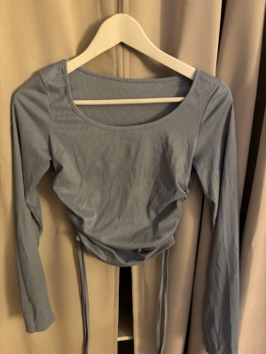 Ljusblå ribbad topp med snörning - Ljusblå långärmad topp med smala ränder och ribbad struktur. Toppen har snörning i sidorna, andvänd ett fåtal gånger men utan prislapp från SHEIN