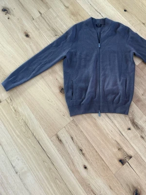 Brun ziptröja, Massimo Dutti - Stilren brun ziptröja från Massimo Dutti med ribbad krage och muddar. Tröjan har två fickor framtill och dragkedja hela vägen. Perfekt till lager på lager och enkel att matcha med olika outfits. Passar M/L.