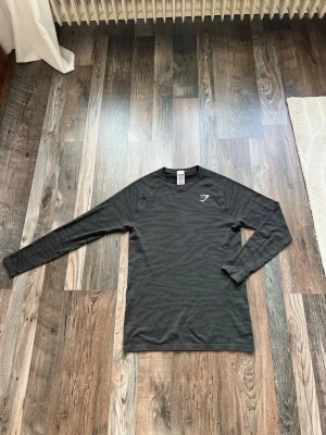 Svart långärmad tröja från Gymshark - Säljer en super Snygg svart tigerrandig långärmad träningströja från Gymshark. Tillverkad i ett lätt och ventilerande material som passar perfekt för träning eller sportaktiviteter. 