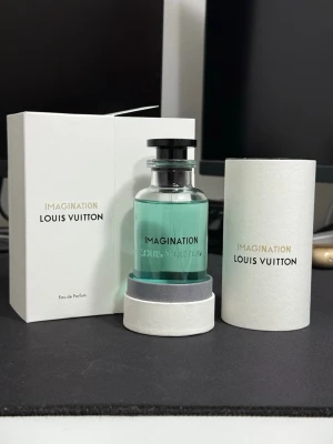 Louis Vuitton Imagination Eau de Parfum 100ml - Louis Vuitton Imagination Eau de Parfum med en stilren glasflaska fylld med ljusblå parfym. Flaskan har svart lock och levereras i exklusiv vit förpackning med guld- och svart text. En lyxig och modern doft för dig som vill sticka ut.