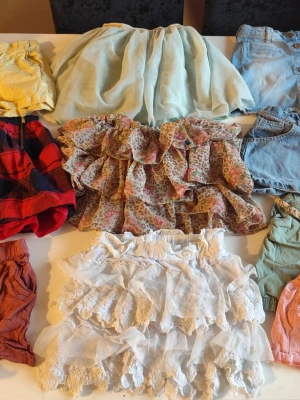 Shorts och kjol paket stl 122/128 - Ett blandat paket med kjolar och shorts i olika stilar och färger. Innehåller bland annat jeanskjolar, tyllkjolar, shorts med resår i midjan och en rutig kjol.  Du är varmt välkommen att kika på mina andra annonser. Sammanfrakt 