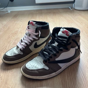 Nike Air Jordan 1 Travis Scott - Hej! Säljer ett par Nike Air Jordan 1 Travis Scott high sneakers med ikonisk omvänd swoosh. I köpet ingår skosnören i färgerna brun, röd, rosa och svart. Samt ett par creeseskydd. Skorna är i fint skick och mycket sparsamt använda och kommer självklart i original kartongen. Skicka för fler bilder 😊