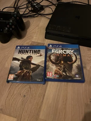 PlayStation 4 Slim med två spel - Säljer en svart PlayStation 4 Slim med två handkontroller och tillhörande kablar. Medföljer gör spelen Hunting Simulator och Far Cry Primal (PS4). Konsolen har en stilren, matt finish och är tillverkad i plast. Perfekt för dig som vill ha en grym spelupplevelse hemma. Laddstation till två kontroller följer med