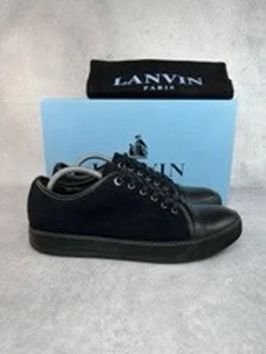 Svarta Lanvin sneakers i mocka och läder - Vi har skorna i 40 och 42. Snygga svarta sneakers från Lanvin med ovandel i mocka och tåparti samt sula i slätt läder. Klassisk låg modell med svarta skosnören och metallfärgade öljetter. Perfekta för dig som gillar stilrena och exklusiva sneakers.