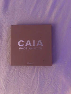 CAIA Face Palette Classy - Säljer en CAIA Face Palette i färgen Classy. Paletten har en stilren, beige fyrkantig förpackning med silvrig text. Perfekt för att skapa en fräsch bas med flera nyanser för ansiktet. Smidig att ta med i väskan och enkel att använda.