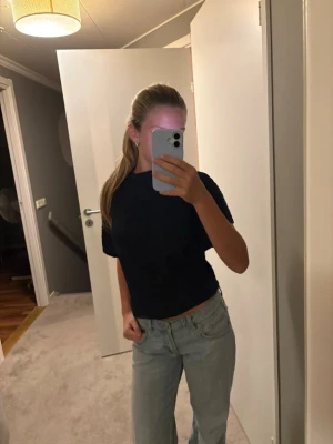 Mörkblå ribbad topp med kort ärm - Säljer en mörkblå ribbad topp med korta ärmar och hög hals. Toppen har en croppad passform och är tillverkad i ett stretchigt material som sitter snyggt på kroppen. Perfekt att styla med jeans eller kjol.
