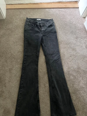 Grå bootcut jeans - Snygga grå bootcut jeans med klassisk femficksdesign och normal midja. Jeansen har en lätt tvättad look och vida ben från knät och ner. Tillverkade i ett mjukt denimtyg som ger en skön passform och cool stil.