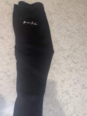 Svarta leggings från Manière De Voir - Snygga svarta leggings från Manière De Voir med diskret logga framtill. De har en hög midja och är tillverkade i ett stretchigt material som sitter tight och bekvämt. Perfekta för en trendig och avslappnad stil.