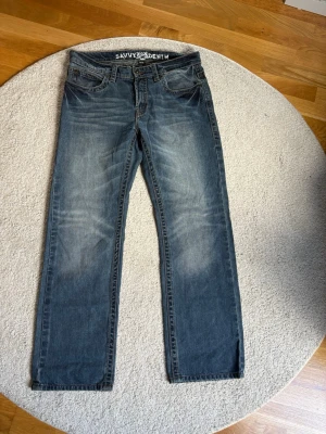 Blå raka jeans från Savvy Denim - Jeansen har snygga slitningar och tvättade detaljer på låren och knäna. Tillverkade i bomull för en skön och avslappnad känsla. 34/32