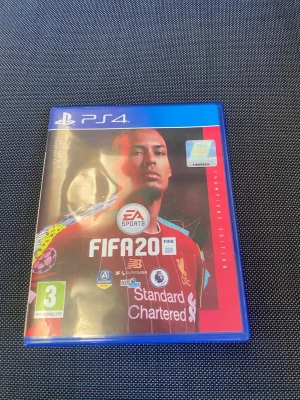 FIFA 20 Champions Edition PS4 - FIFA 20 Champions Edition till PS4 med blå plastfodral. Omslaget har en fotbollsspelare i röd tröja och spelet är märkt med PEGI 3. Skivan är röd med FIFA 20-logga och PS4-märkning. Perfekt för dig som gillar fotbollsspel och vill spela med vänner.