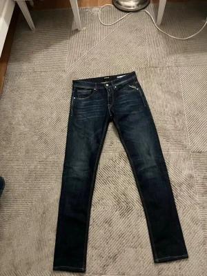 Mörkblå Replay jeans slim fit - Säljer ett par mörkblå jeans från Replay i modellen Willbi med regular slim fit. Jeansen har klassisk femficksdesign, snygga slitningar och kontrastsömmar. Perfekta för dig som gillar en smalare passform och tidlös stil.