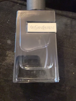 Yves Saint Laurent Y Eau de Parfum - Y Eau de Parfum från Yves Saint Laurent är en elegant herrdoft i en stilren, mörk glasflaska med metallisk detalj. Flaskan rymmer 100 ml och har en modern, maskulin design med tydlig YSL-logga på både flaska och förpackning.