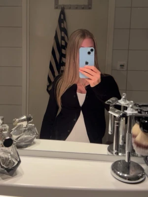 Svart cardigan från H&M, XS - En klassisk svart cardigan från H&M i storlek XS. Tröjan har knappar framtill och långa ärmar.
