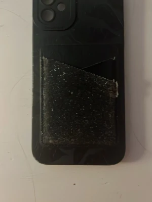 Svart mobilskal med kortfack (Iphone11) - Snyggt svart mobilskal med inbyggt kortfack på baksidan. Skalet har en matt finish och är designat för att skydda mobilen samtidigt som du enkelt kan förvara kort. Passar perfekt för dig som vill ha allt samlat på ett ställe. Priset kan diskuteras.