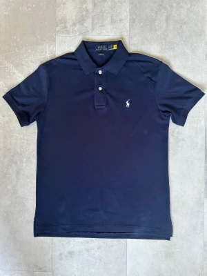 Blå pikétröja från Polo Ralph Lauren - Klassisk marinblå pikétröja från Polo Ralph Lauren som är helt ny utan lappar. Passar perfekt till många olika stilar. Den är regular fit och storlek S. Om du letar efter den perfekta piken för ett rimligt pris så har du kommit rätt