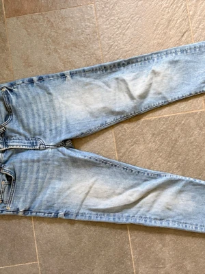 Ljusblå  jeans från dressman - Säljer ett par ljusblå jeans med klassisk femficksmodell. Jeansen har slitningar och tvättade detaljer framtill för en trendig look. Materialet är stretchigt denim som sitter tajt längs benen. Perfekta till en avslappnad streetstyle.