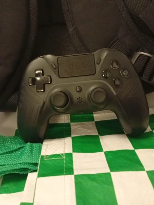 Svart handkontroll till PS4 - Säljer en svart handkontroll från Deltaco Gaming med modern design. Kontrollen har två styrspakar, styrkors, touchpad och klassiska knappar. Tillverkad i plast med mattsvart finish och diskreta mönster på framsidan. Perfekt för gaming på konsol eller PC.