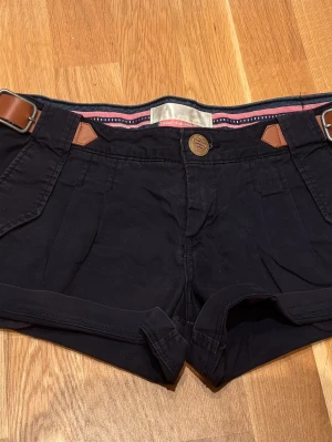 Lågmidjade shorts  - Mörkblåa lågmidjade shorts med bruna bältdetaljer. Perfekta för sommaren!