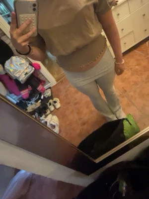 Beige croppad topp med ribbad kant - Säljer en beige croppad topp med ribbad, stretchig midja och korta ärmar. Toppen har en avslappnad passform och är perfekt för dig som gillar en enkel men trendig stil. Materialet känns mjukt och bekvämt, troligen bomull eller en bomullsblandning.