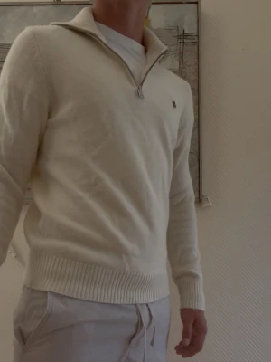 Beige halvzip tröja med broderad logga från Morris - Beige stickad halvzip från Morris. Tröjan är i näst intill nytt skick och har inga tecken på användning. Modellen på bilden är 175cm och väger 75kg. På bilden bär modellen storlek S. Hör gärna av er vid funderingar!😄