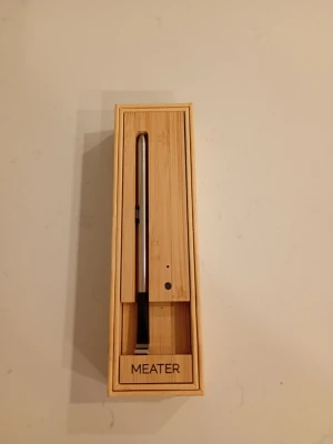 Meater Bluetooth Köttermometer - Fungerar som ny. Säljes då jag fick ny i present. Meater är den första helt trådlösa termometern. Den läser dels av i mitten av proben i köttets kärna (max 100°C) men den mäter också i andra änden av proben temperaturen i ugnen/grillen (max 275°C) och beräknar på det viset hur lång tid som det är kvar till önskad innertemperatur. Proben är vattentät och du spolar enkelt av den i rinnande vatten. Batteritid är mellan 24 - 48 timmar. Fungerar lika bra i ugn som grill.