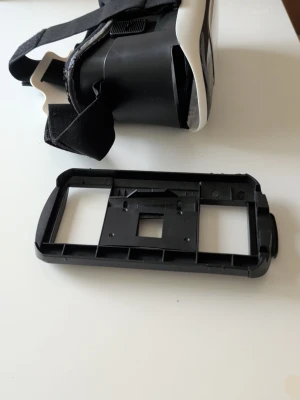 Svartvita VR-glasögon med remmar - VR-glasögon i svart och vitt med justerbara elastiska remmar och löstagbar frontpanel. Tillverkade i plast och skumgummi för bekväm passform. Perfekt för att uppleva VR-spel och appar med din smartphone. I Mycket bra skick knappt använd.
