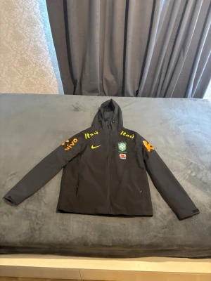 Brazil nike Windbreaker  - Säljer Nike Brasil Windbreaker – helt ny. Jackan är i toppskick och endast provad. Anledningen till att jag säljer den är att den tyvärr är lite för liten för mig. Mycket hög kvalitet. Skicka gärna meddelande vid intresse eller om du vill ha fler bilder.