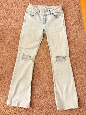 Ljusblå jeans från Nelly - Säljer mina ljusblåa jeans från Nelly med hål i vid knäna. I storlek 34. Köpta för 699kr, säljer för 250kr.