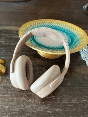 Beige over-ear hörlurar från Skullcandy - Snygga over-ear hörlurar från Skullcandy i beige färg. De har mjuka, vadderade kåpor och justerbart huvudband med tygdetalj på insidan. Perfekta för musik, gaming eller poddar. Trådlös design och stilren look.